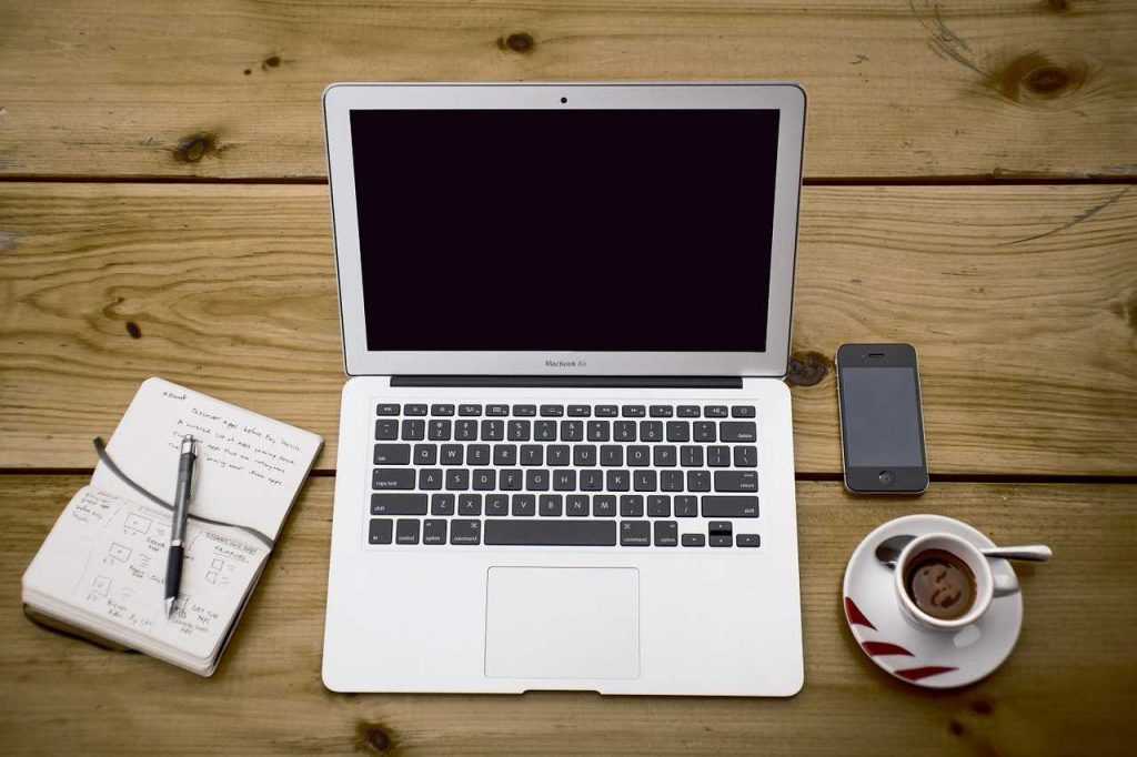 laptop na stole, kawa, telefon komórkowy i notatnik, oferty pracy